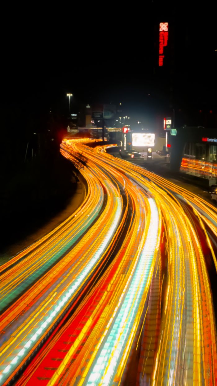 Vivid long exposure photo capturing colorful light trails on a busy city highway at night.